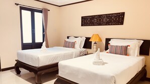A hotel room with two beds, a window with curtains, a decorative wall piece, and a bedside lamp. - Na Thapae Chiangmai Hotel (Chiang Mai)