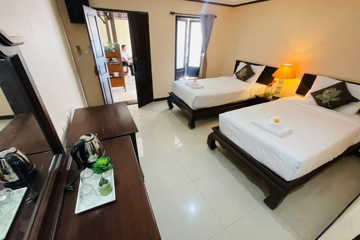 A hotel room with two beds, a desk, and a mirror.