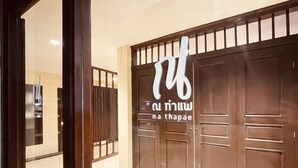 A hotel entrance with a large wooden door and a glass window. - Na Thapae Chiangmai Hotel (Chiang Mai)