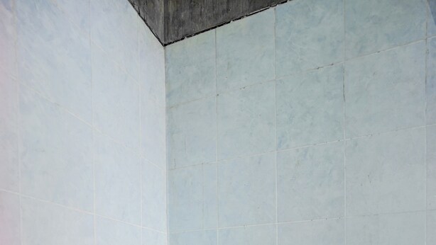 Un baño pequeño y funcional con inodoro sencillo y baldosas de suelo con diseño.
