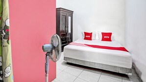 A bedroom with a bed, a wardrobe, and a standing fan. - OYO Life 92840 Wisma Morricco  (Jogoroto)