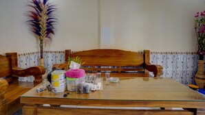 A dining area with a wooden table, chairs, a decorative feather, and a vase with flowers. - OYO Life 92840 Wisma Morricco  (Jogoroto)