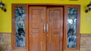 Una puerta doble de madera con paneles de vidrio, en una pared de piedra y color amarillo.
