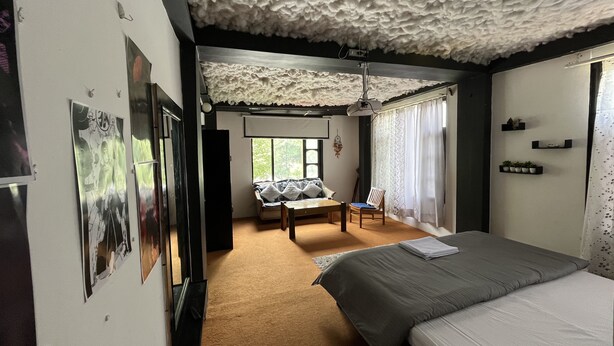 Une chambre à coucher comprenant un lit, un canapé, un fauteuil et un plafond orné d’un motif texturé.