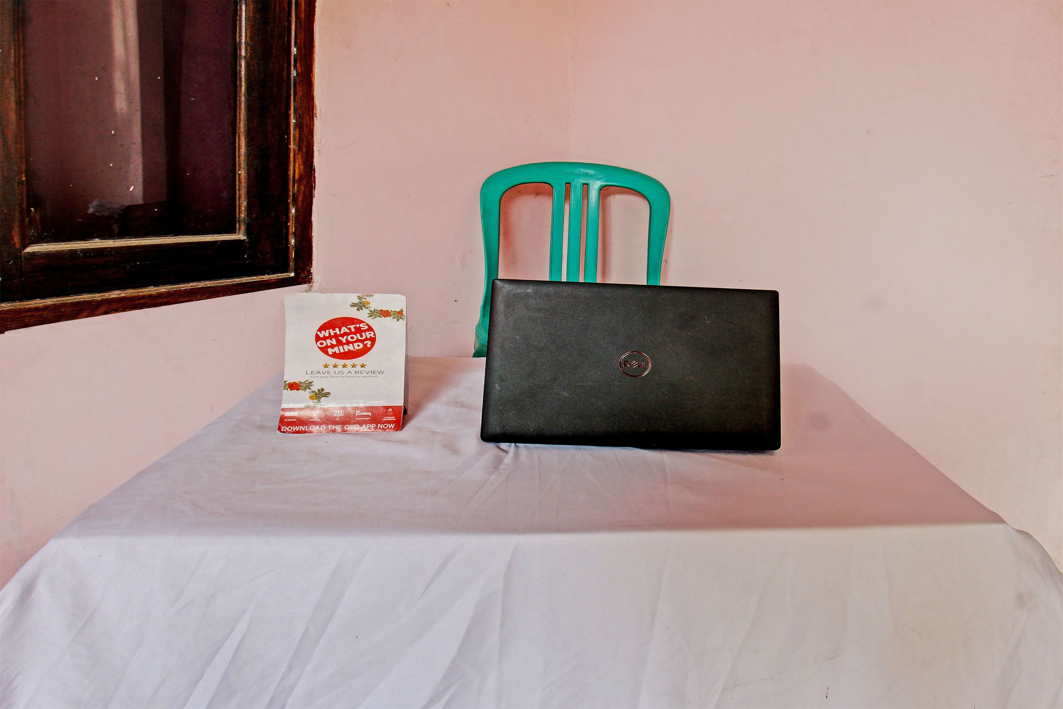 A laptop on a table with a chair and a box.