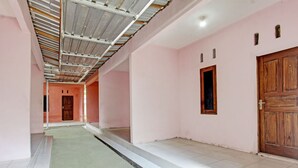 A corridor with pink walls, a wooden door, and a tiled floor. - OYO Life 93058 Kos Subur (Tanjung)