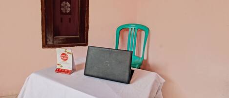 A laptop on a table with a white tablecloth, a green chair, and a sign with text.
