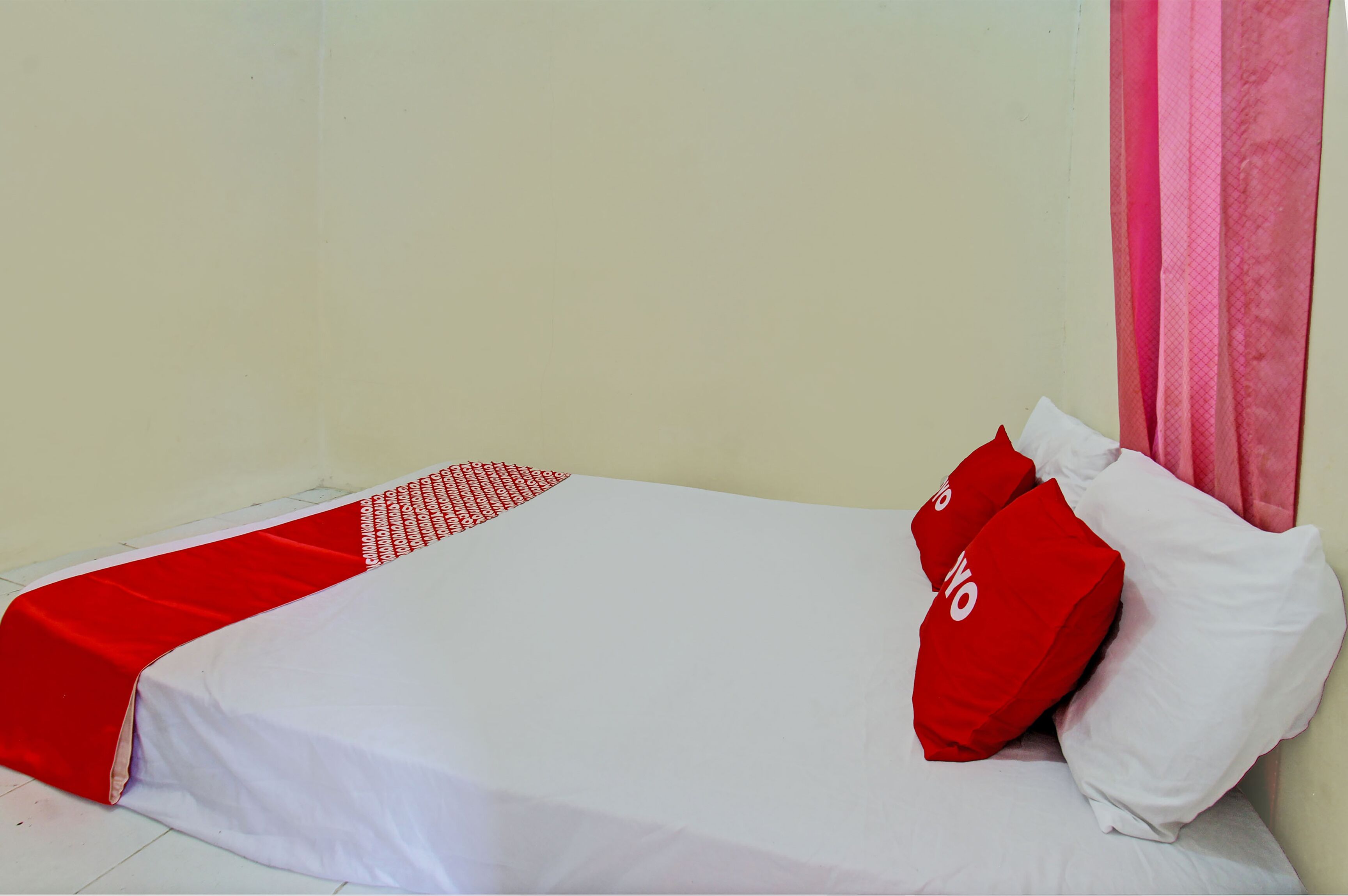 A bed with a white bedspread and red accents, including a red pillow and a red blanket.