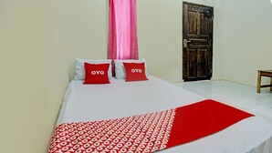 A bed with white bedding and red pillows, a red patterned blanket, and a wooden door in the background. - OYO Life 93058 Kos Subur (Tanjung)