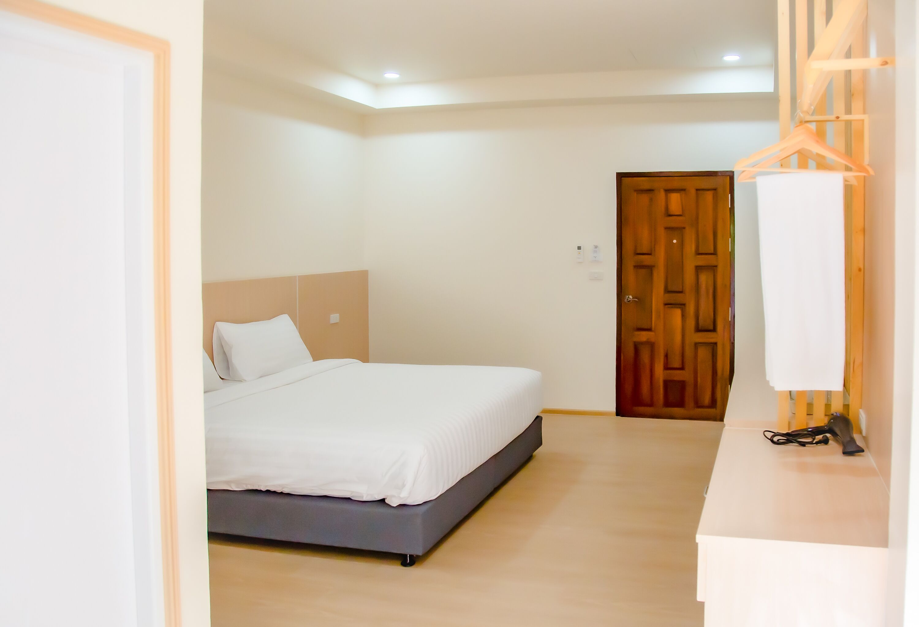 A bedroom with a bed, a wooden door, and a white wall.