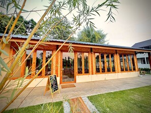 A wooden structure with large windows, a chalkboard sign, and a grassy area in front. - น่าน ม่วนใจ Nan Muanjai Hotel (Pua)