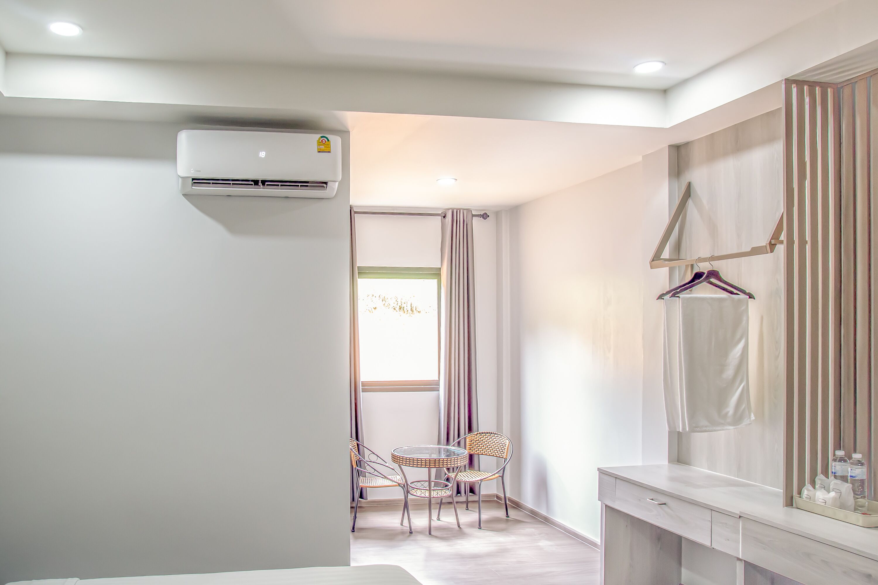 A modern bathroom with a built-in air conditioner, a vanity with a mirror, and a seating area with chairs.