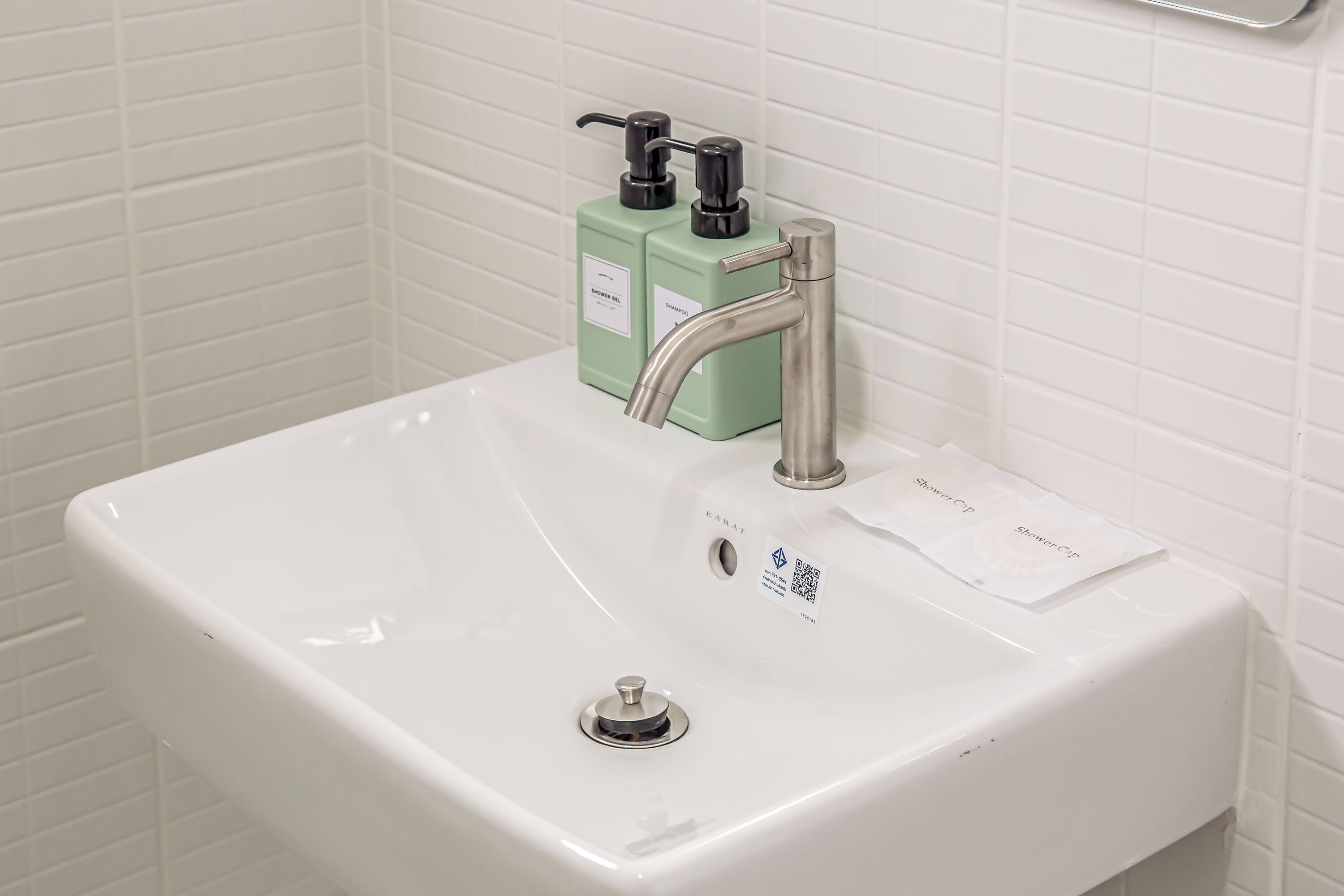 A white bathroom sink with a modern faucet and two green soap dispensers.