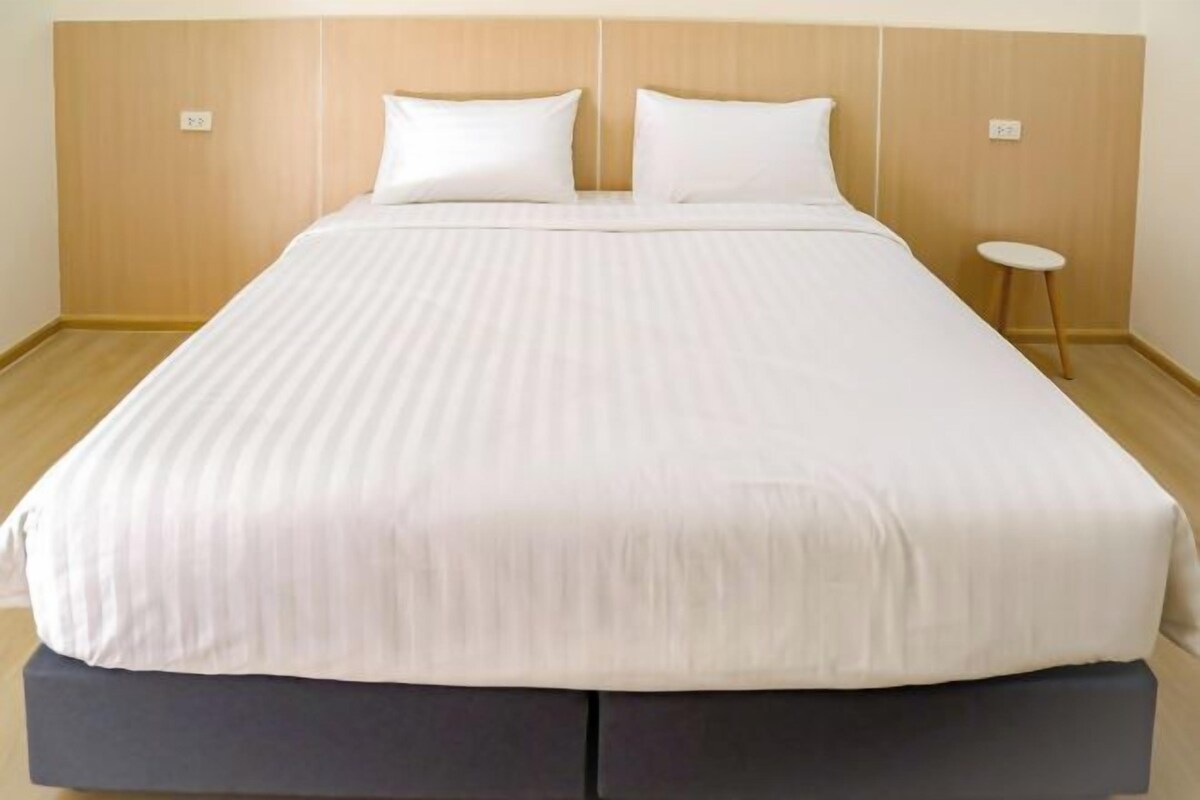 A neatly made bed with a wooden headboard, two pillows, and a small round table beside it.