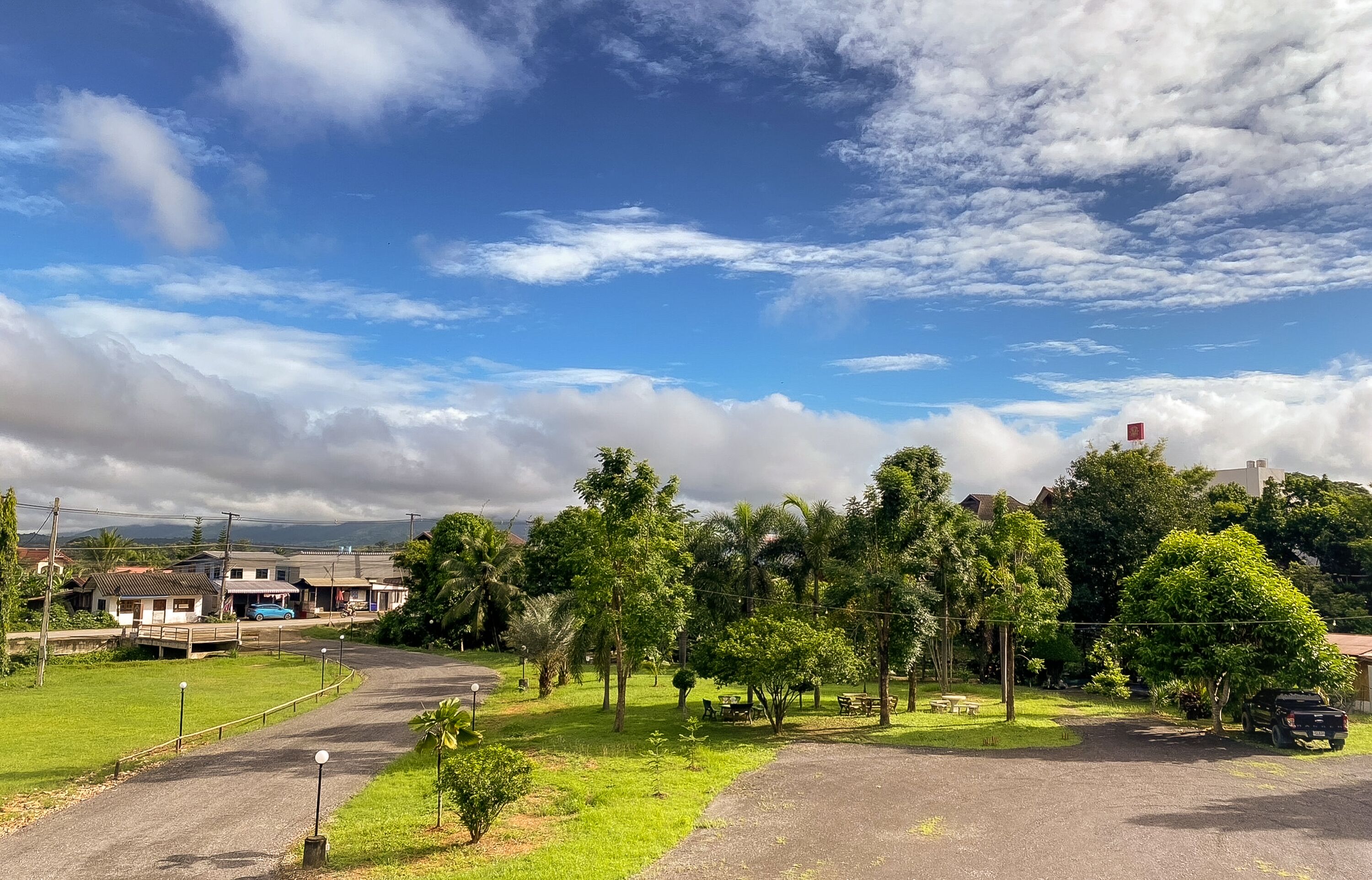 A residential area with houses, a paved driveway, and a grassy area with trees.