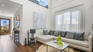 Una sala de estar moderna con un sofá, una mesa de centro y un ventanal con cortinas.