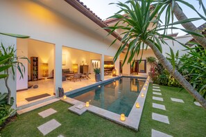 A modern house with a swimming pool, outdoor seating, and well-lit interior spaces. - Villa Amandaru (Legian)