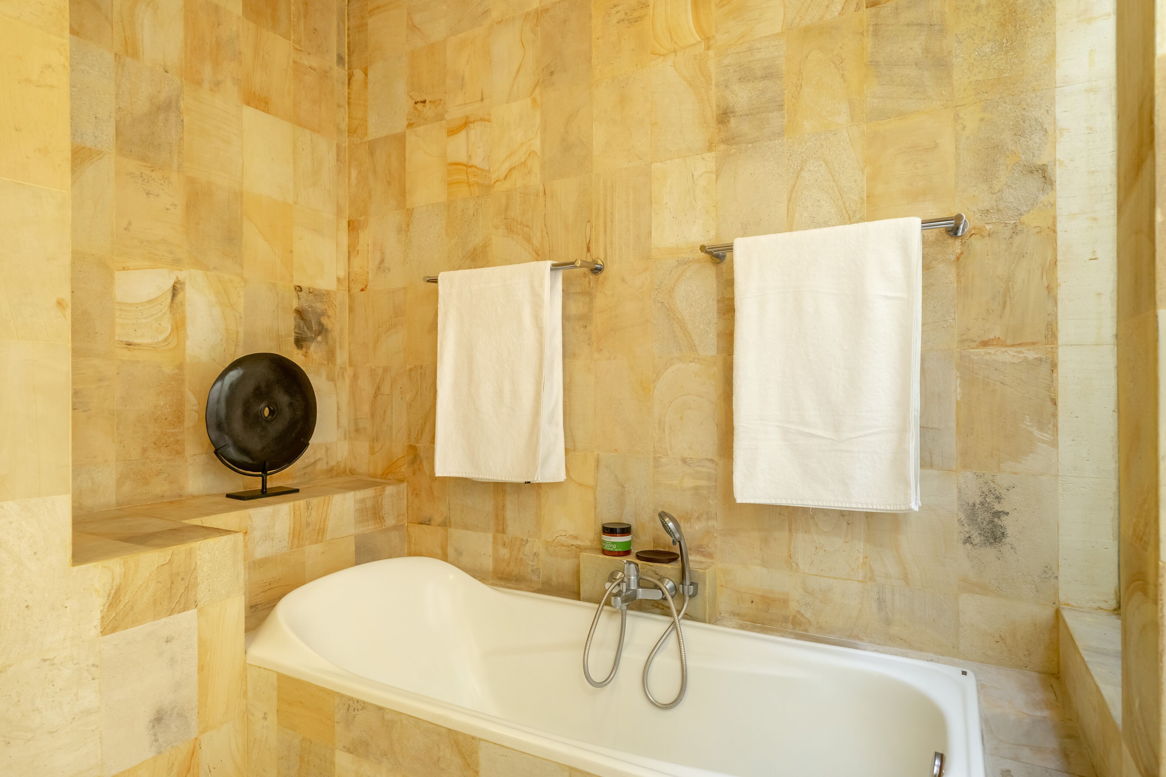 A bathroom with a bathtub, two towels, and a soap dish on the wall.