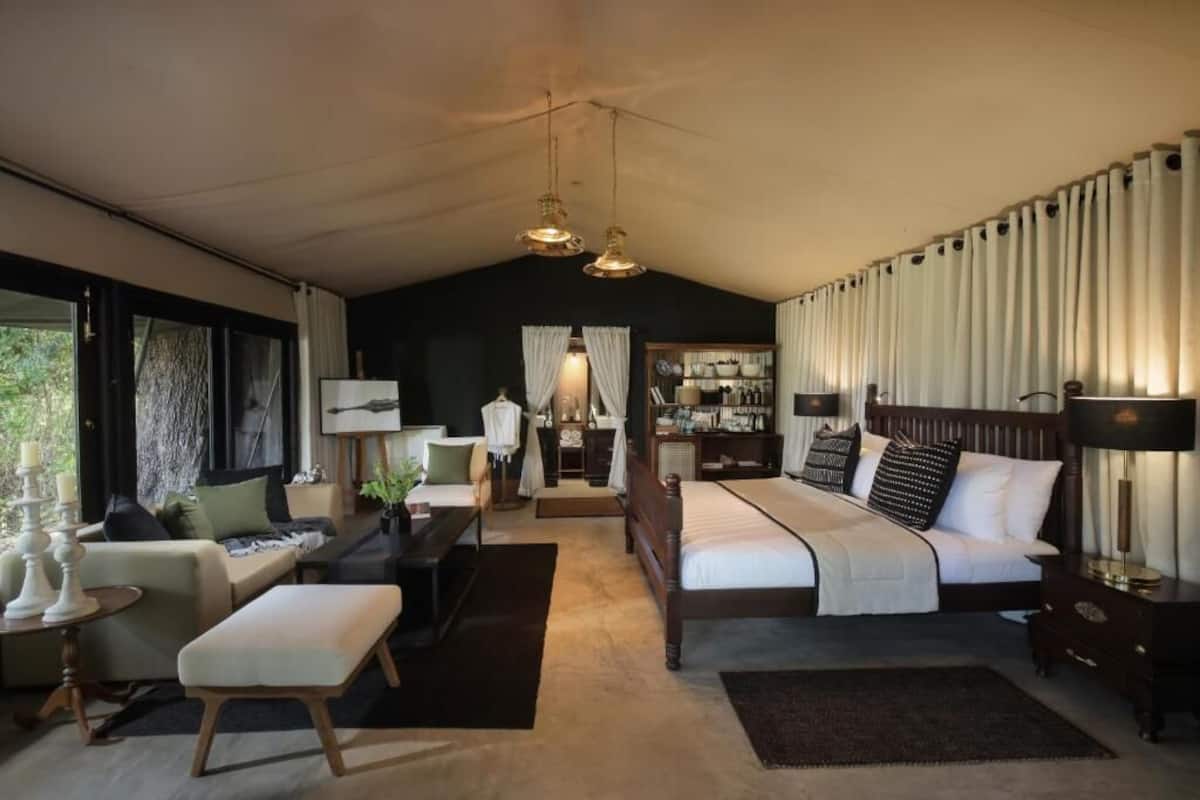 A modern bedroom with a large bed, a sofa, a desk, and a television.