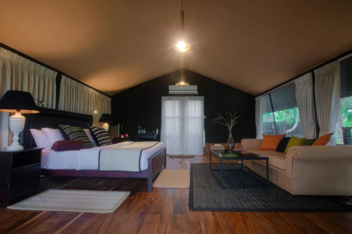 A bedroom with a bed, bedside tables, a sofa, a coffee table, and a window with curtains.