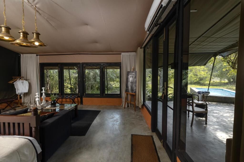 Habitación amplia con un gran ventanal, una piscina visible a través del vidrio y un comedor con mesa y sillas.