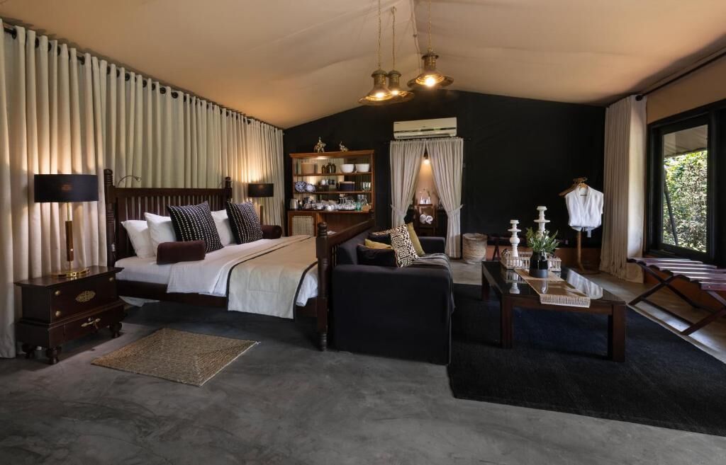 A spacious bedroom with a large bed, a seating area, and a bookshelf.