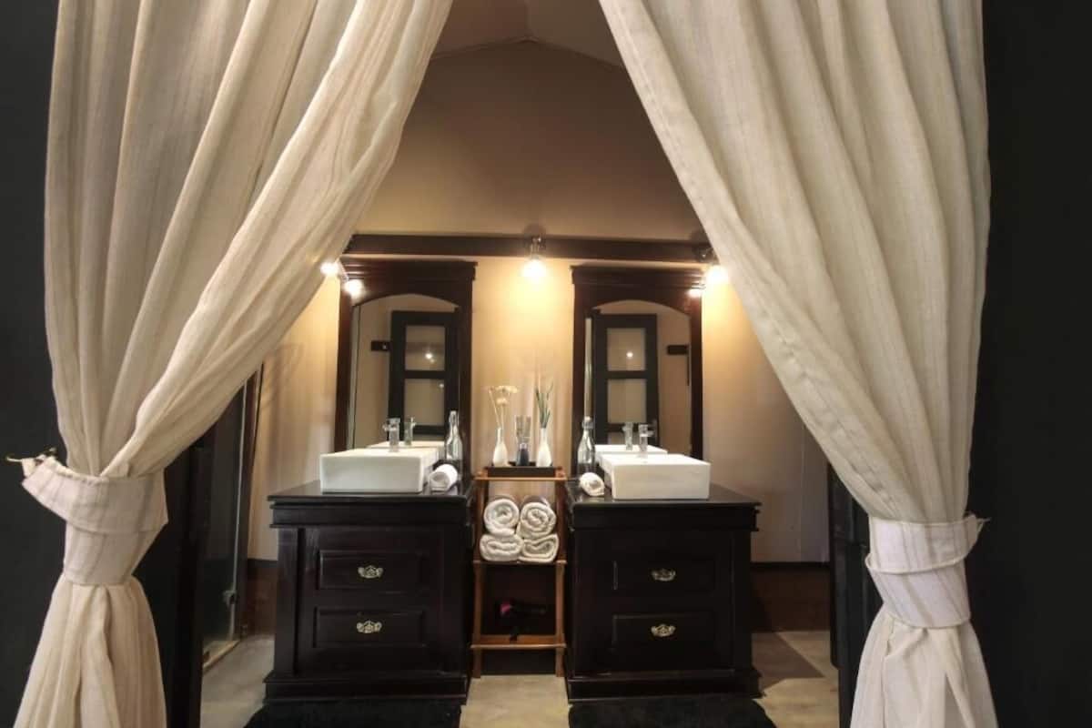 A luxurious bathroom with two dark wooden sinks, a central mirror, and a vanity with a towel rack.