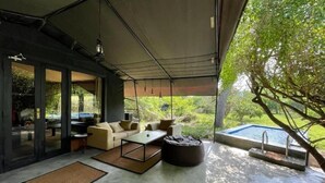 A modern outdoor living area with a sofa, coffee table, and a small pool. - Leopard Trails Yala (Kataragama)