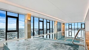 Ein modernes Hallenbad mit Blick auf die Stadt, großen Fenstern und blauem Himmel.