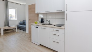 A modern kitchen with white cabinets, a dishwasher, a sink, and a small countertop. - Apartments Budimir (Vir)