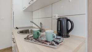 A kitchenette with a sink, two mugs, a kettle, and a magazine on a tray. - Apartments Budimir (Vir)