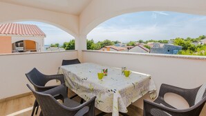 A balcony with a table and chairs, a view of houses, and a clear sky. - Apartments Budimir (Vir)