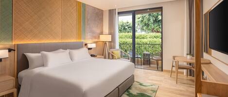 Una habitación de hotel moderna con una cama grande, un balcón con mobiliario exterior y una televisión.