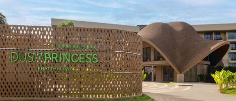 A modern building with a unique curved roof and a sign that reads "DUSITPRINCESS PHATTHALUNG".
