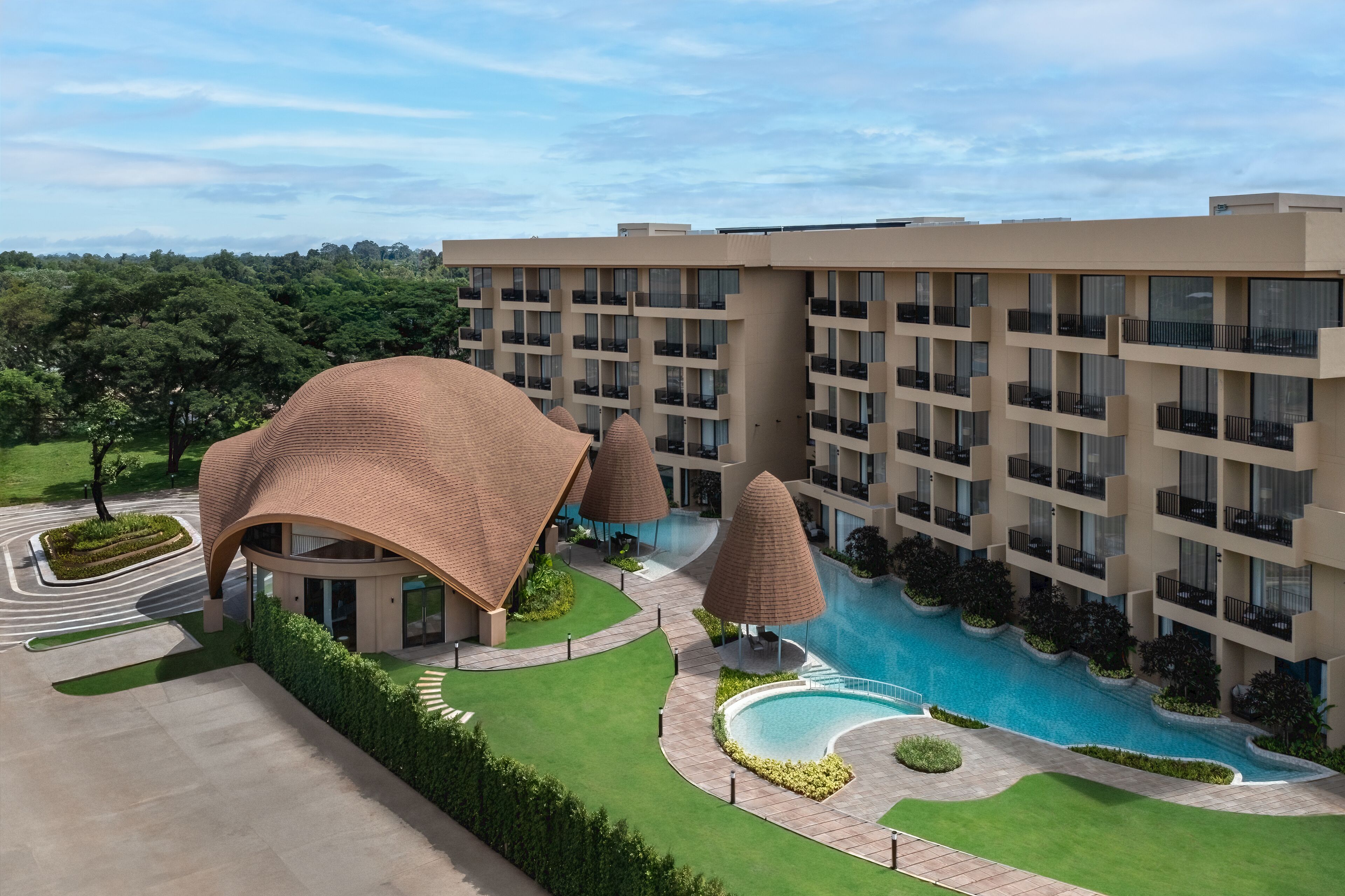 Un hotel con piscina, varios balcones y jardín ajardinado.