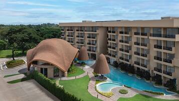 Un hotel con piscina, varios balcones y jardín ajardinado.