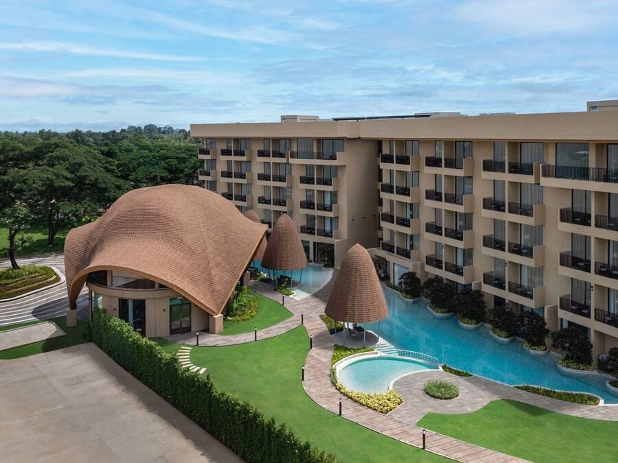 Un hotel con piscina, varios balcones y jardín ajardinado.
