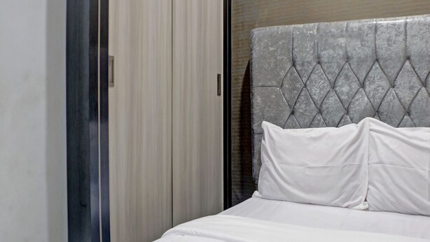 A bedroom with a bed, a grey headboard, and a sliding door. - OYO Life 92830 Homestay Slamet Riadi Iv (Bandar Lampung)