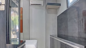 A small, modern room with a bed, a vanity with a mirror, a sink, and a large window. - OYO Life 92830 Homestay Slamet Riadi Iv (Bandar Lampung)