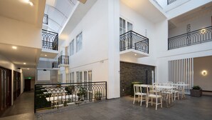Un vaste espace intérieur comprenant plusieurs étages, des balcons et un coin repas avec des tables et des chaises.