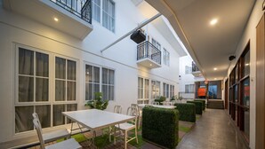 Une terrasse extérieure moderne, dotée d’un espace repas, de chaises disposées avec soin et d’une petite table.