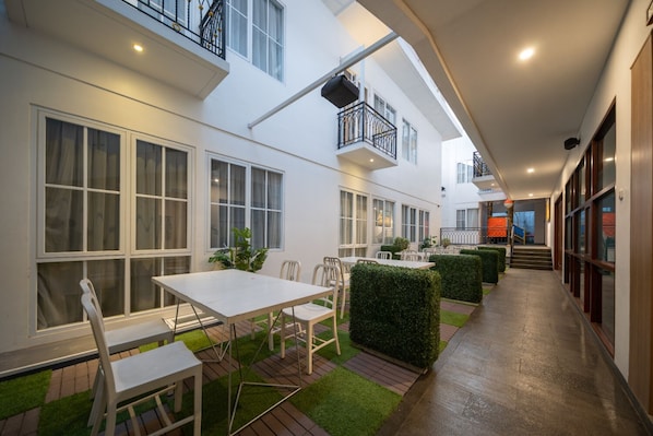 A modern outdoor patio with a dining area, neatly arranged chairs, and a small table. - Cove Bening Boutique (Bekasi)