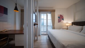 Une chambre d’hôtel avec un lit, une table de chevet, une lampe et une vue sur le balcon extérieur.