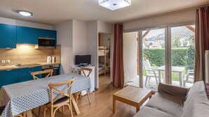 A compact living space with a kitchenette, dining area, and a sofa.