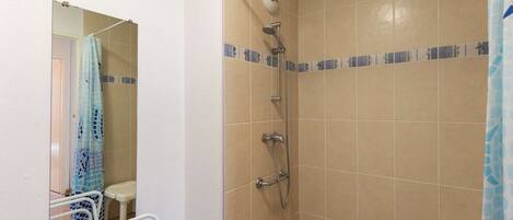 A small, tiled bathroom with a shower, a toilet, and a sink.