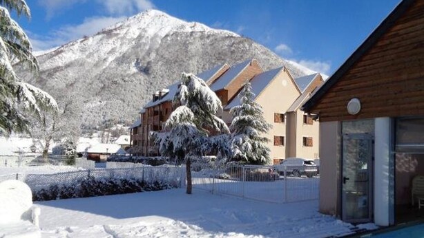 A hotel with a pool, surrounded by snow-covered trees and mountains.