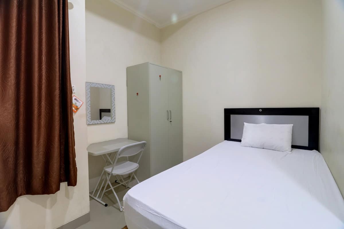 A bedroom with a bed, a desk, a chair, and a wardrobe.