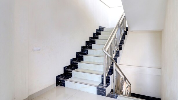 A staircase with black and white marble steps and a metal railing. - OYO Life 92707 D-akomiba Residence (Jambi)