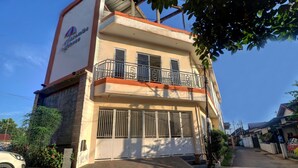 A two-story building with a balcony on the second floor, a large garage door, and a sign on the side. - OYO Life 92707 D-akomiba Residence (Jambi)