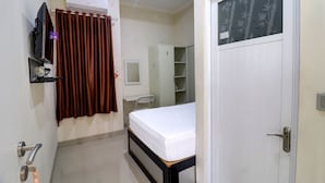A bedroom with a bed, a TV, an air conditioner, a wardrobe, and a door with a bamboo-patterned window. - OYO Life 92707 D-akomiba Residence (Jambi)